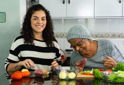 Candid Moment of Latina Woman Cooking with Elderly Afro Grandmother at Home