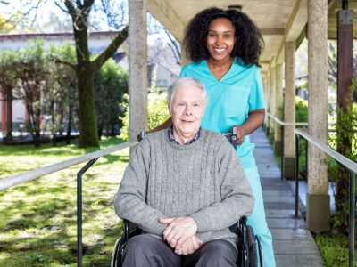 African nurse helping man on the wheelchair.